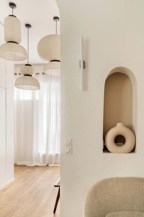 A modern interior with pendant lights, a white wall with a recessed shelf, and a wooden floor.