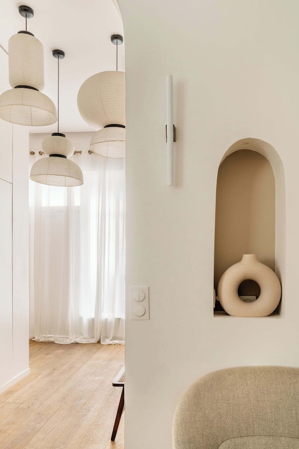 A modern interior with pendant lights, a white wall with a recessed shelf, and a wooden floor.