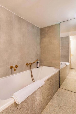 A modern bathroom with a freestanding bathtub, a large mirror, and a towel.
