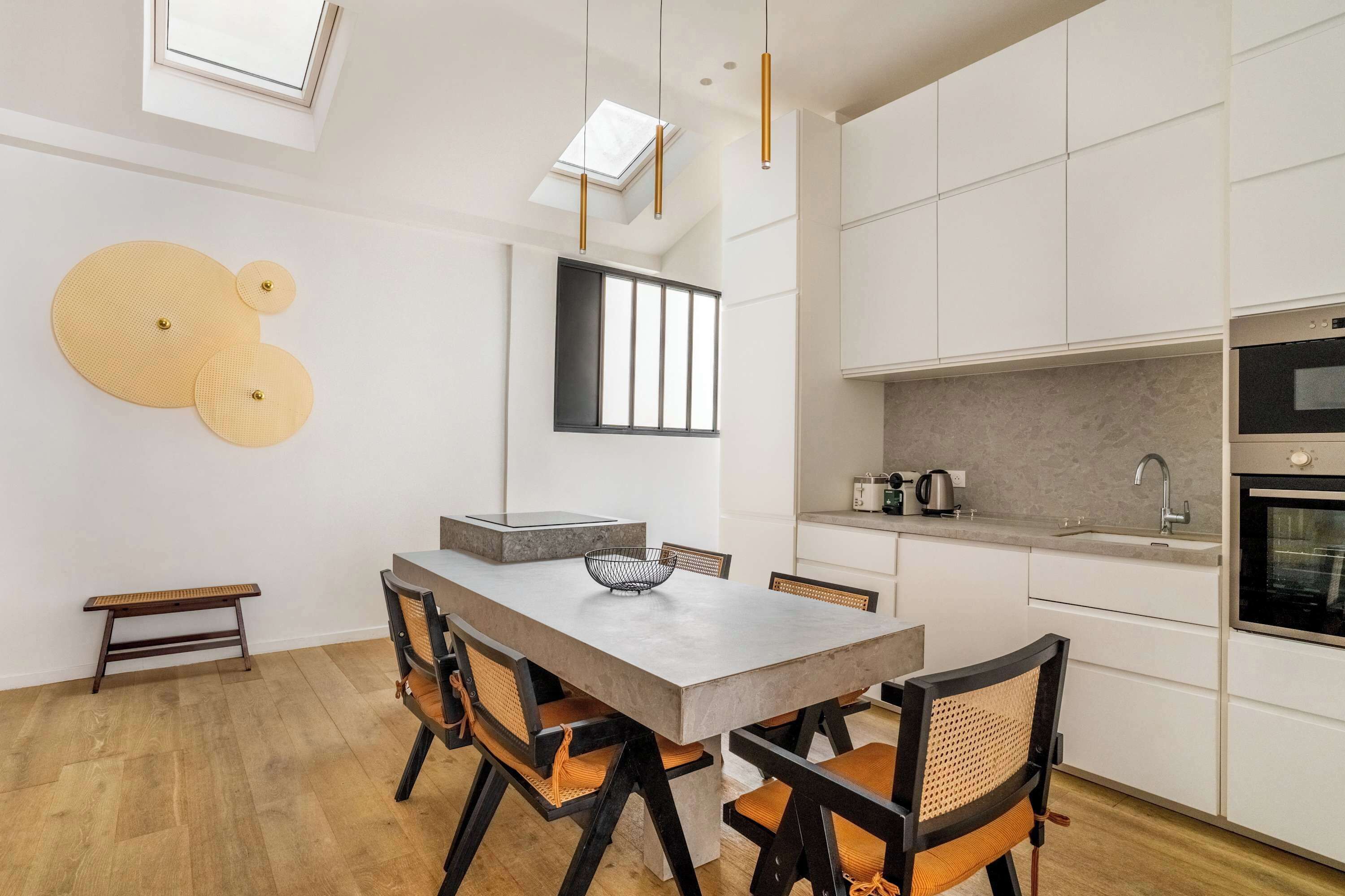 A modern kitchen with white cabinets, a built-in oven, and a window above the sink.