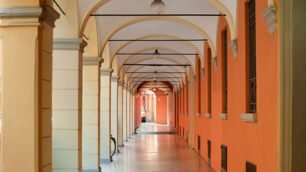 A corridor with arched ceilings and columns, leading to a central open space. - PETRONIUS HOME STUDIO (Bologna)