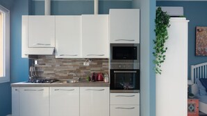 A modern kitchen with white cabinets, a brick backsplash, and stainless steel appliances. - PETRONIUS HOME STUDIO (Bologna)