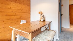 Un mur en bois, une table en bois avec un banc, une lampe suspendue et une porte.