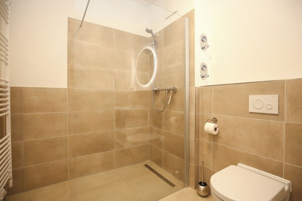 A bathroom with a shower, toilet, and towel rack.