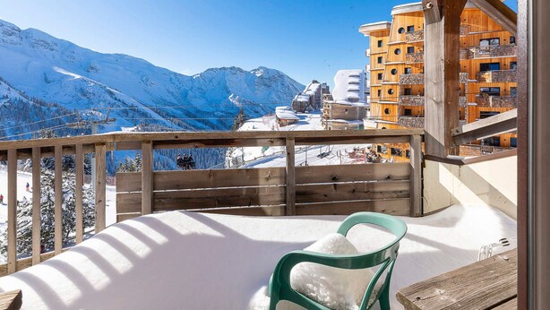 Un balcon donnant sur des montagnes enneigées et un bâtiment en bois doté de balcons.