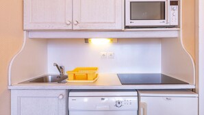 Une petite cuisine équipée d’un four à micro-ondes, d’un petit évier et d’un lave-vaisselle.
