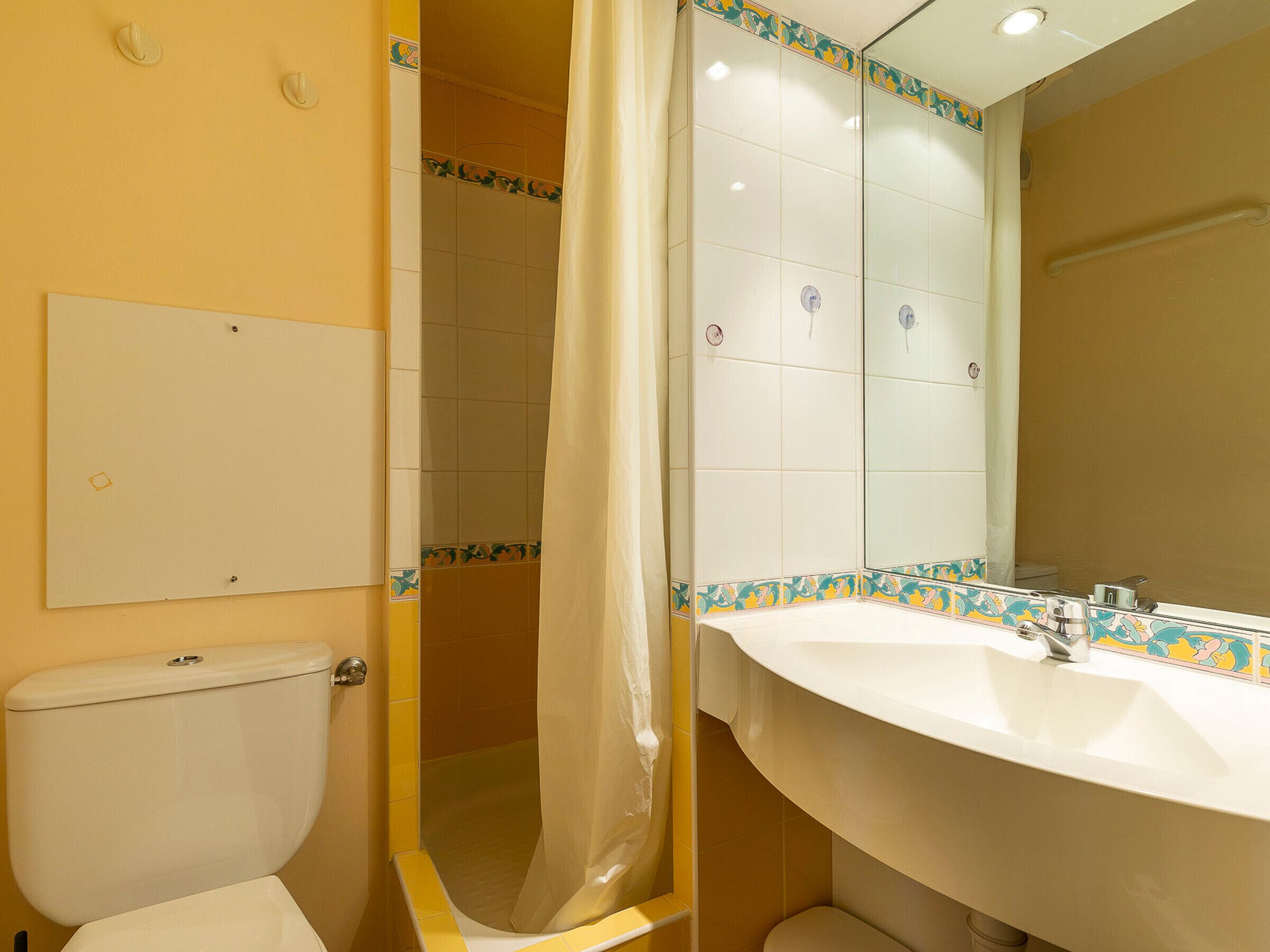 A bathroom with a toilet, shower, and sink.
