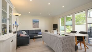 Ein modernes Wohnzimmer mit einer Couch, einem Esstisch und einem Fernseher.