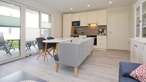 Eine moderne Küche mit weißen Schränken, einem eingebauten Backofen und einem Essbereich mit einer Bank und einem Tisch.