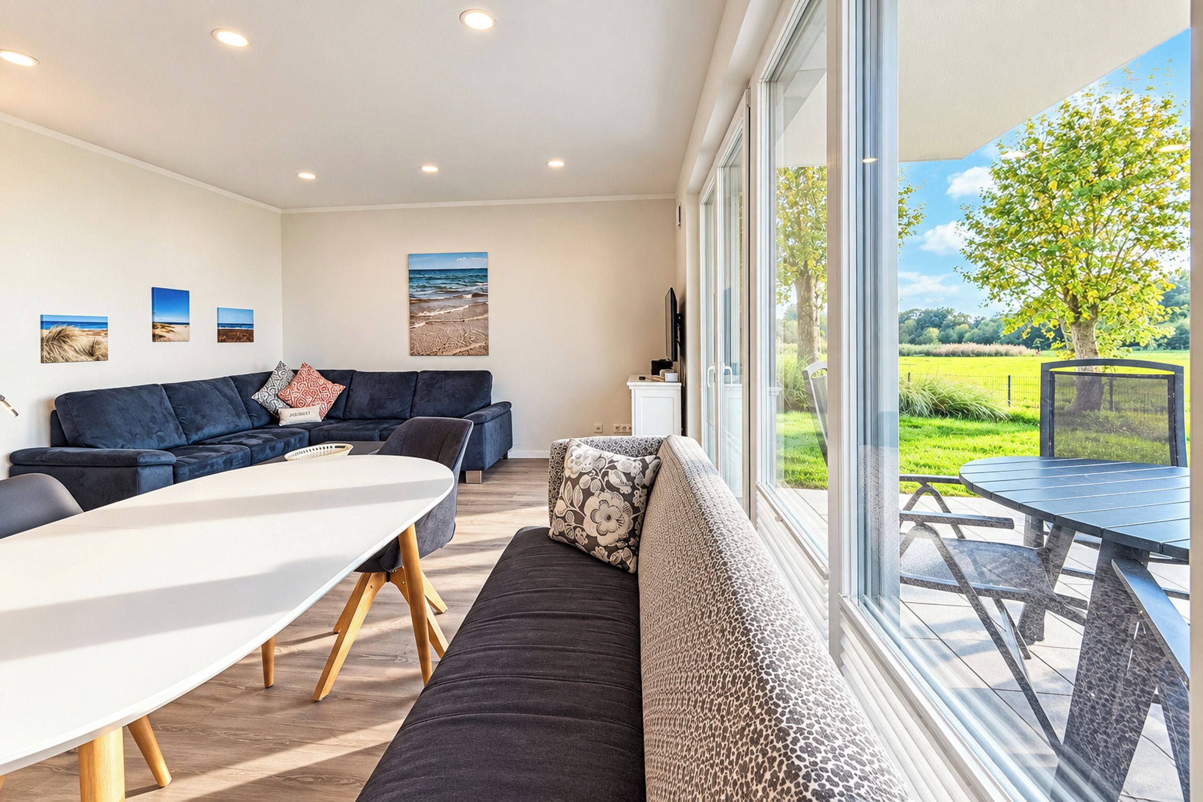 Una sala de estar moderna con un sofá, una mesa de comedor y un ventanal con vistas a un jardín.