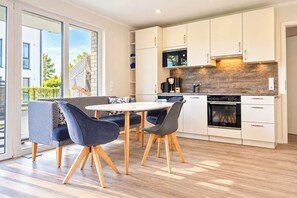 A modern kitchen with white cabinets, a built-in oven, and a coffee machine.