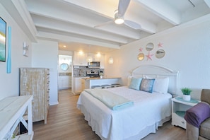 A bedroom with a large bed, a nightstand, a dresser, and a ceiling fan.