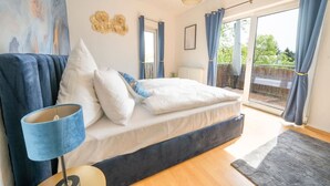 A bedroom with a bed, a nightstand, a lamp, and a view of the outdoors through a sliding glass door. - Penthouse-Suite near University (Gießen)