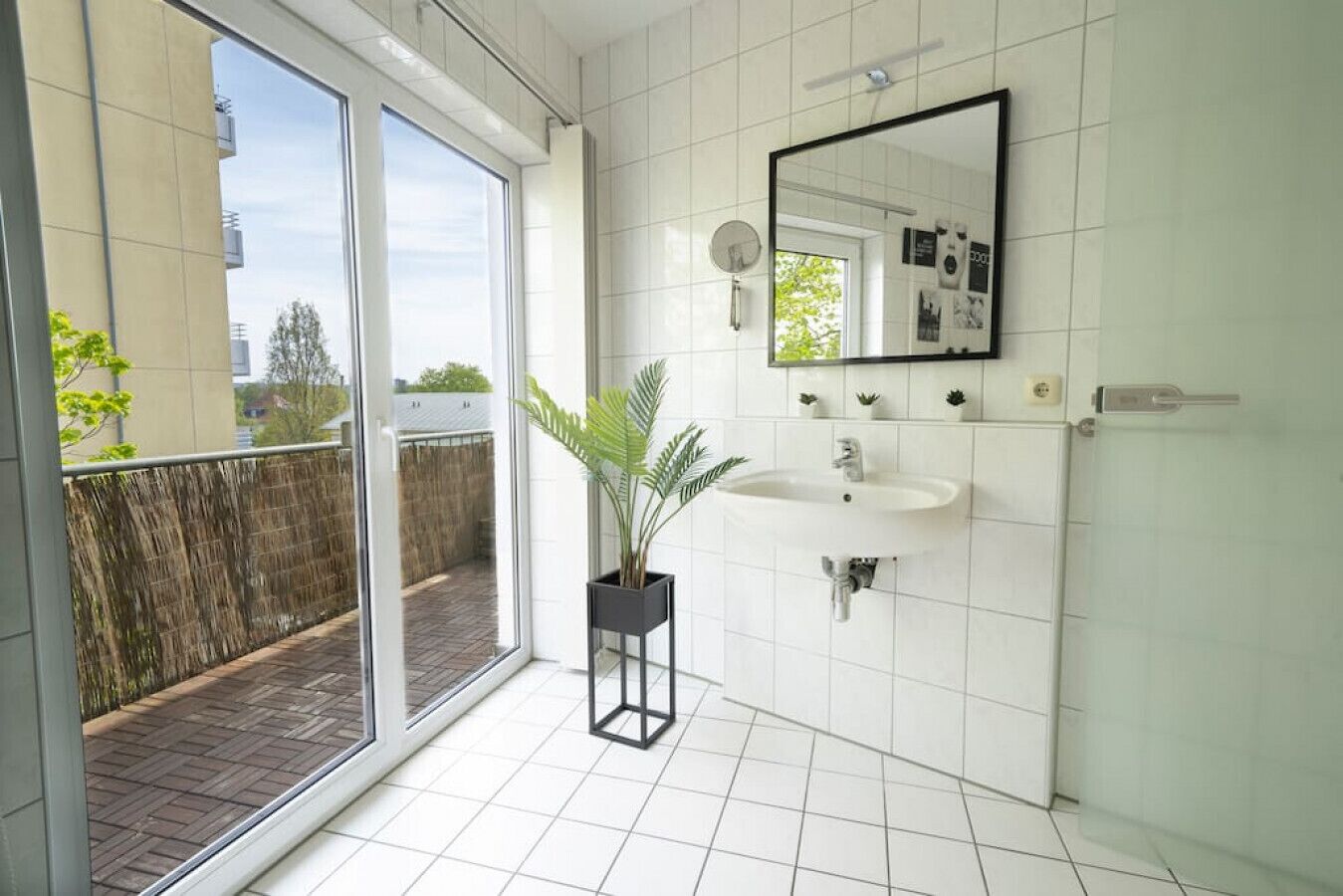 Ein modernes Badezimmer mit großem Fenster, Waschbecken und Spiegel.