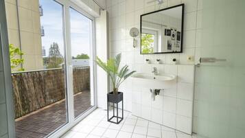 Ein modernes Badezimmer mit großem Fenster, Waschbecken und Spiegel.
