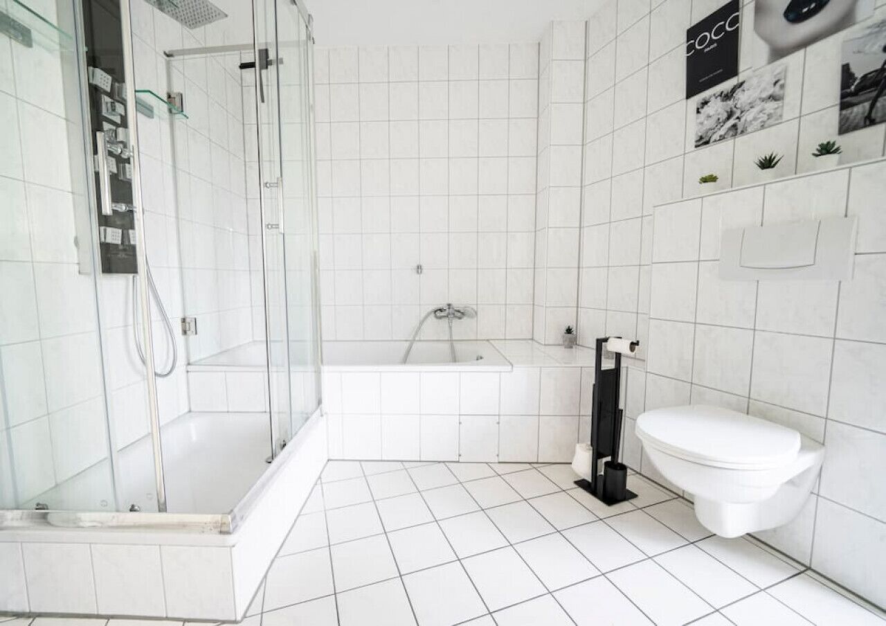 Een moderne badkamer met een douche met glazen wand, een bad en een toilet.