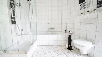 Een moderne badkamer met een douche met glazen wand, een bad en een toilet.