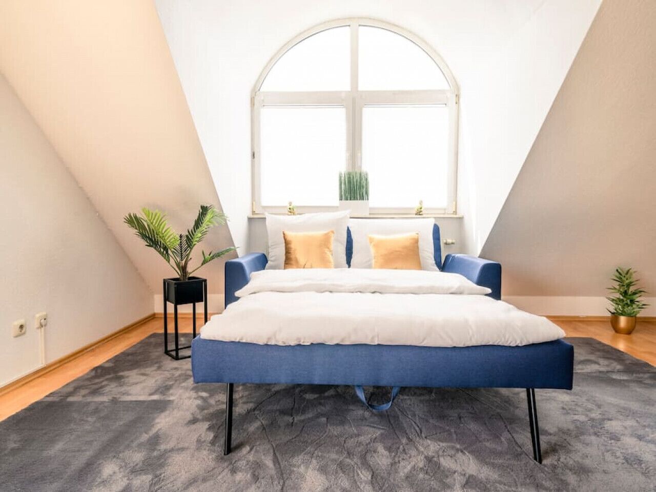 Une chambre à coucher avec un lit, une fenêtre et deux plantes en pot.