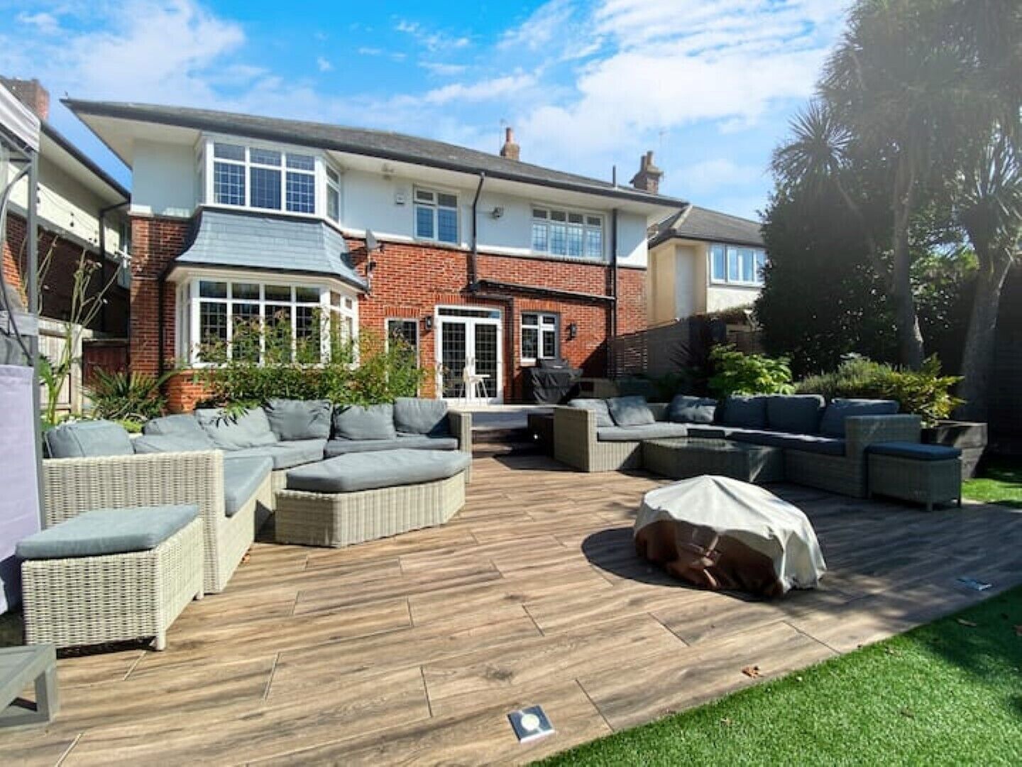 A spacious patio with outdoor furniture, a covered barbecue area, and a well-maintained lawn.