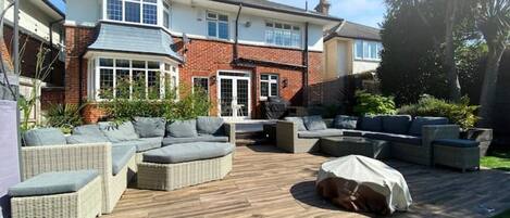 A spacious patio with outdoor furniture, a covered barbecue area, and a well-maintained lawn.