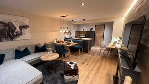A modern living room with a sofa, a round coffee table, and a cow-themed artwork on the wall. - Willkommen in der Gemütlichen Ferienwohnung Bergidyll (Oberstaufen)
