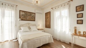 Un dormitorio amplio con una cama grande, una araña y obras de arte en las paredes.
