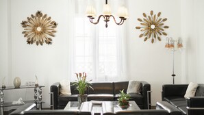 Una sala moderna con un conjunto de sofá, una mesa de centro, decoración en la pared y un candelabro.