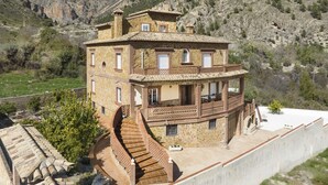 Un edificio de piedra con una escalera de caracol, un balcón y vistas a un paisaje montañoso.
