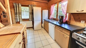 A compact kitchen with a refrigerator, dishwasher, stove, and a sink. - Comfortable 3-star apartment, large terrace and private parking (Le Corbier)
