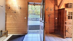 A wooden interior with a door leading to an outdoor area, a tiled floor, and a wooden cabinet. - Comfortable 3-star apartment, large terrace and private parking (Le Corbier)