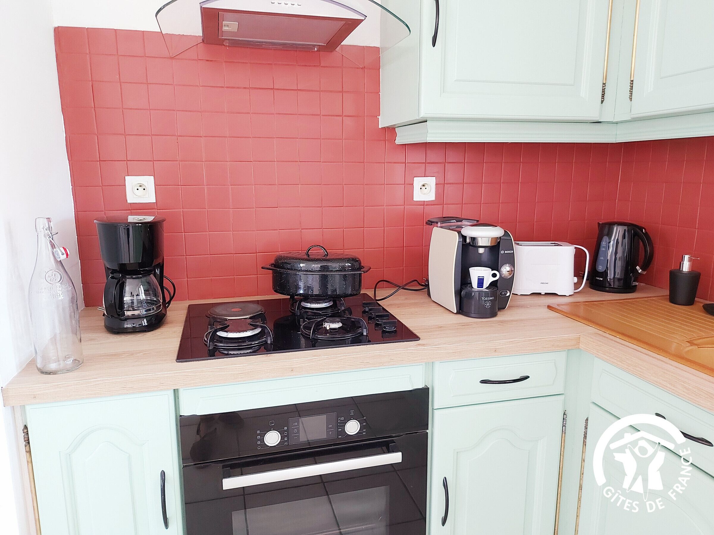A kitchen with a gas stove, a coffee maker, a toaster, and an oven.