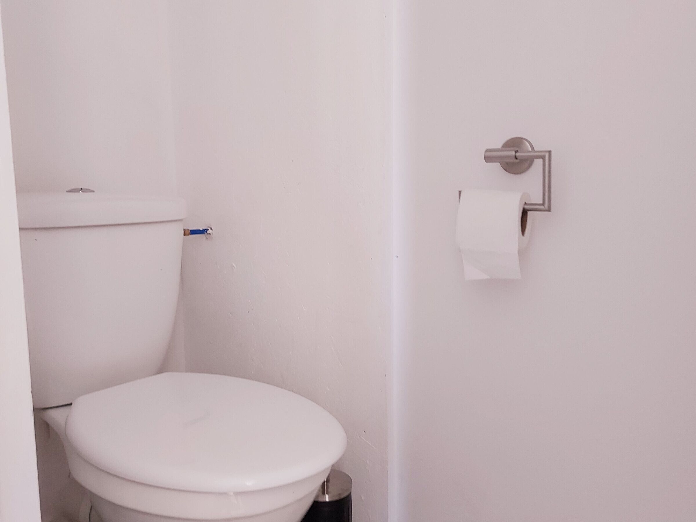 Een kleine, witte badkamer met een toilet en een papieren handdoekdispenser aan de muur.