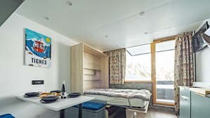 A compact room with a bed, a dining table, and a kitchenette. - Comfortable studio ski-in/out with balcony and WIFI (Tignes)