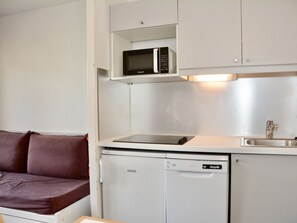 Una kitchenette compacta equipada con microondas, un refrigerador pequeño y un lavamanos.