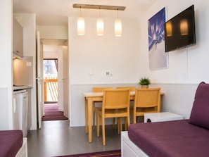 Una habitación moderna con comedor, sofá, televisión y cocina.