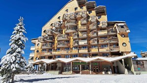 A multi-story building with balconies and a ski resort setting.