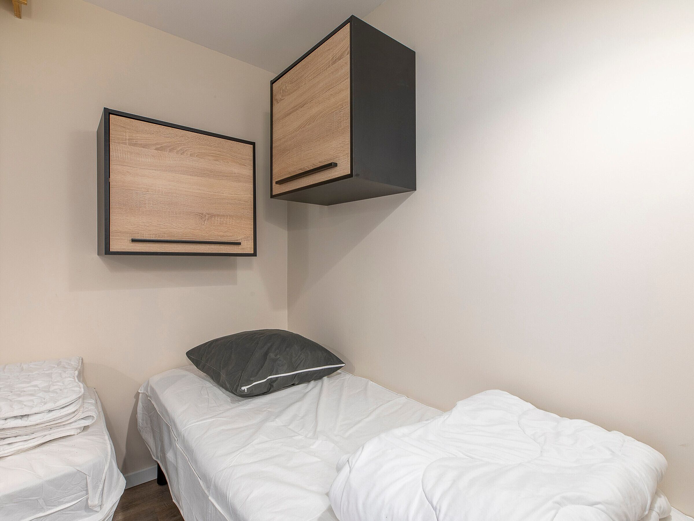 A bedroom with a bed, a pillow, and two framed pictures on the wall.