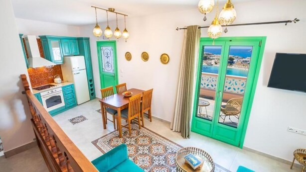 A modern apartment with a kitchen, dining area, and balcony with a view.