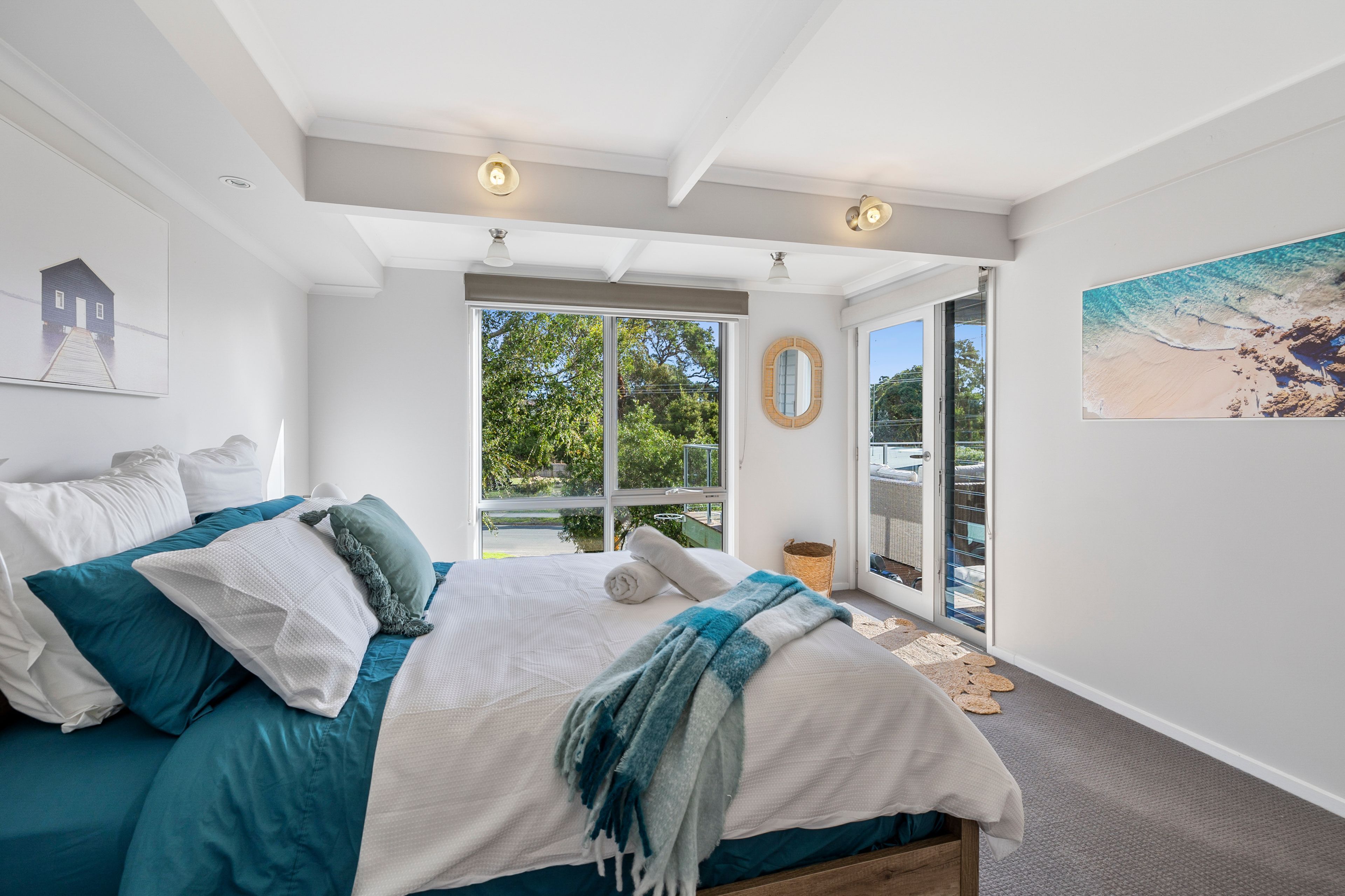 Quarto com cama grande, vista para o exterior e um quadro na parede.