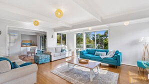 A spacious living room with a large blue sofa, a white sofa, and a beige sofa. There is a wooden coffee table in the center.