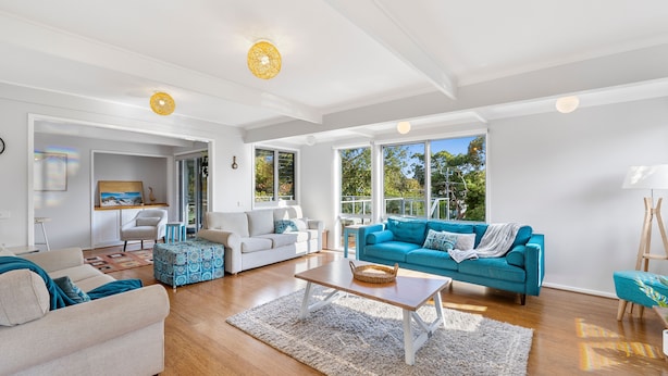 A spacious living room with a large blue sofa, a white sofa, and a beige sofa. There is a wooden coffee table in the center.