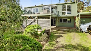 A two-story house with a balcony, a fenced yard, and a covered carport.