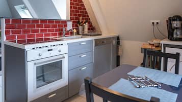 Cocina compacta con horno integrado, lavabo y cafetera.
