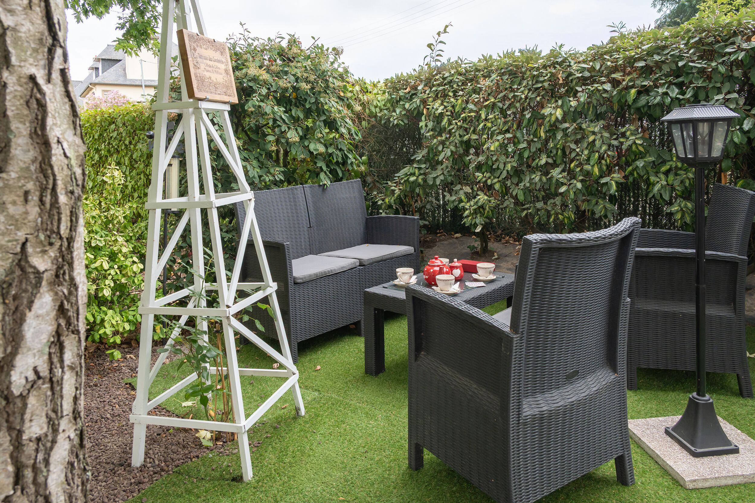 Une terrasse avec des meubles en osier, une échelle et une table préparée pour le thé.