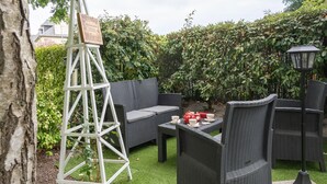 A patio with wicker furniture, a ladder, and a table set for tea. - Cancale - Côte D'émeraude (Cancale)