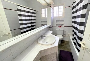 Un baño con un lavamanos blanco, un inodoro y una bañera.
