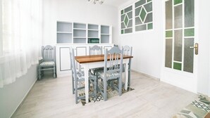 Un comedor con una mesa y sillas de madera, una araña y un armario blanco con estantes.