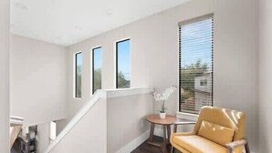 A modern room with a staircase, a yellow sofa, a small table with a plant, and large windows. - Spacious 5 Bedroom Dallas Home for Families (Dallas)