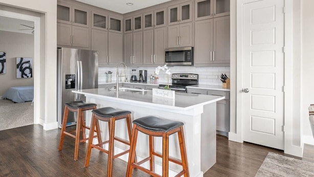 A modern kitchen with a large island, stainless steel appliances, and wooden bar stools. - Spacious 5 Bedroom Dallas Home for Families (Dallas)