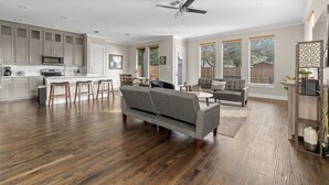 A spacious living area with a kitchen, a grey sofa, and a ceiling fan. - Spacious 5 Bedroom Dallas Home for Families (Dallas)